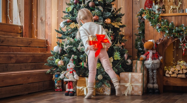 Niña bonita abre el regalo de navidad.