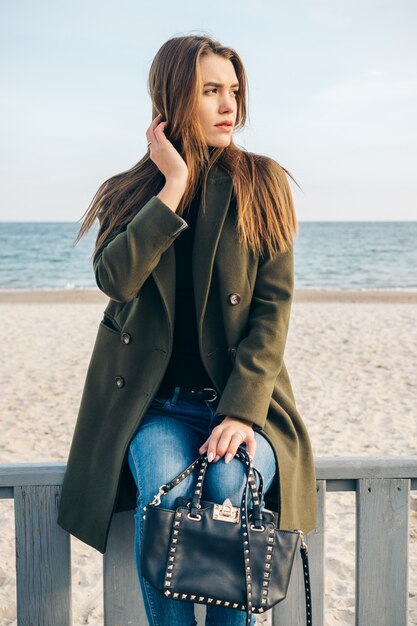 Niña bonita en abrigo verde con una bolsa