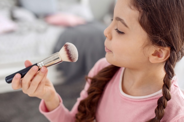 Niña bonita actuando como una maquilladora frente a la cámara