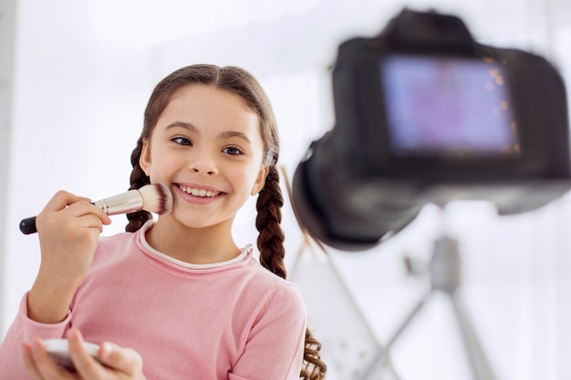 Niña bonita actuando como una maquilladora frente a la cámara