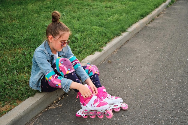 Niña bonita aprendiendo a patinar en un hermoso día de verano en un parque