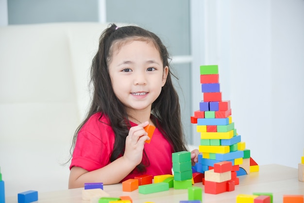 Niña bonita asiática jugando con coloridos bloques de madera en casa