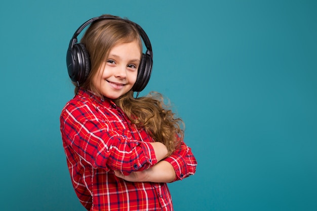 Niña bonita con camisa a cuadros y auriculares con cabello castaño