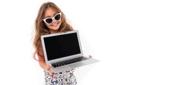 Niña bonita caucásica con gafas de sol y portátil, pianorama aislado sobre fondo blanco.