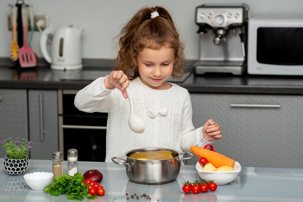 Una niña bonita cocina en la cocina con verduras frescas Fotografía conceptual