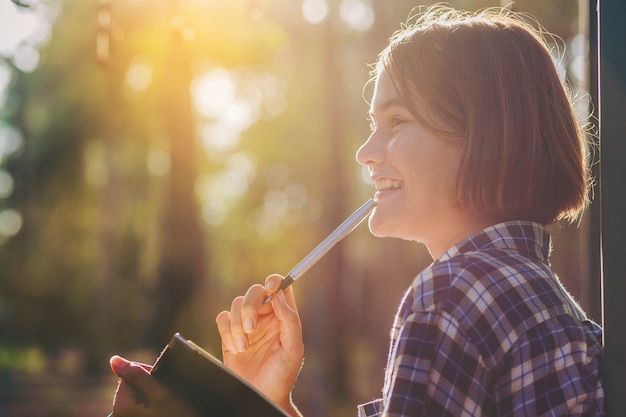 La niña bonita con el cuaderno hace una breve nota mientras viaja educación a lo largo del camino