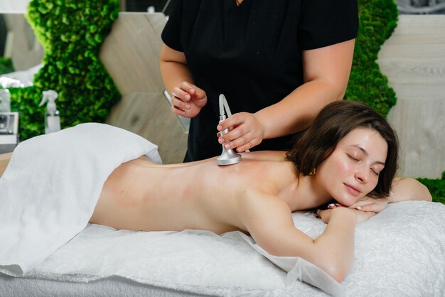 Una niña bonita disfruta de un masaje profesional al vacío en el Spa. Cuidado del cuerpo. Salón de belleza.