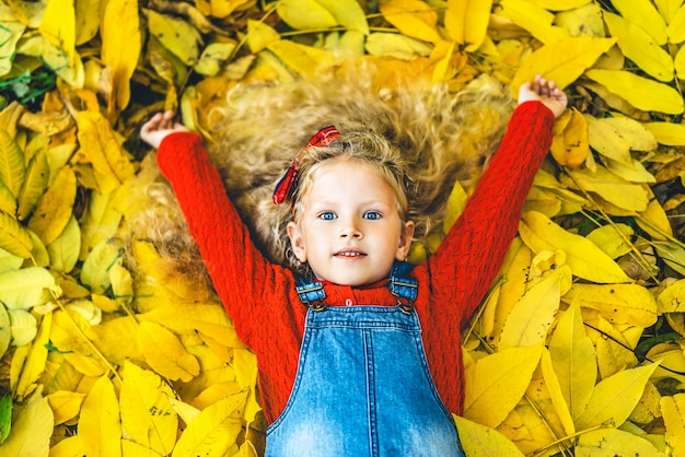 La niña bonita se divierte en el parque, tiempo del otoño.