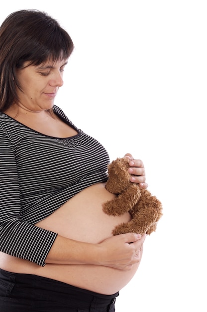 Foto niña bonita embarazada con teddy sobre un fondo blanco