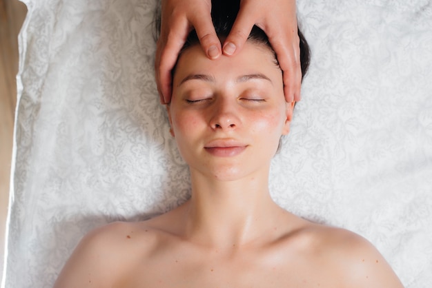 Una niña bonita está disfrutando de un masaje de cabeza profesional en el Spa