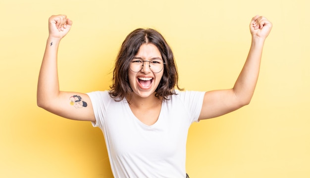 Niña bonita gritando triunfalmente, con aspecto de ganador emocionado, feliz y sorprendido, celebrando