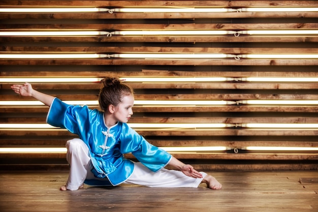 Niña bonita en la habitación en ropa deportiva para artes marciales es Wushu o kung fu