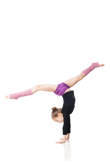 Niña bonita haciendo gimnasia sobre fondo blanco.