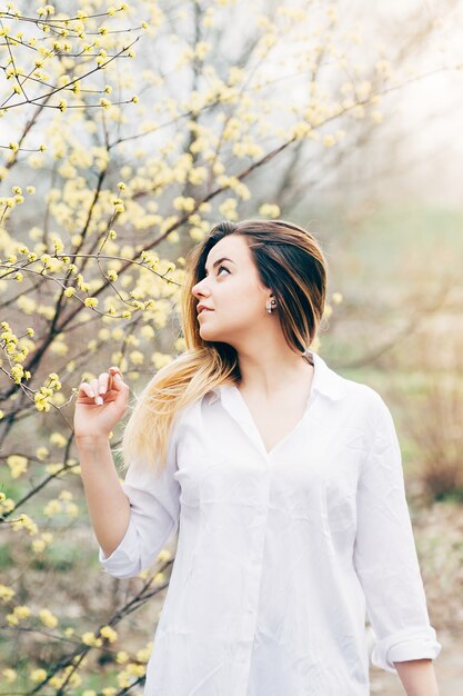 Una niña bonita en un jardín disfruta de árboles florecientes