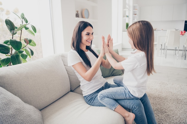 Niña bonita y joven mami aplaudir los brazos juegan en casa interior