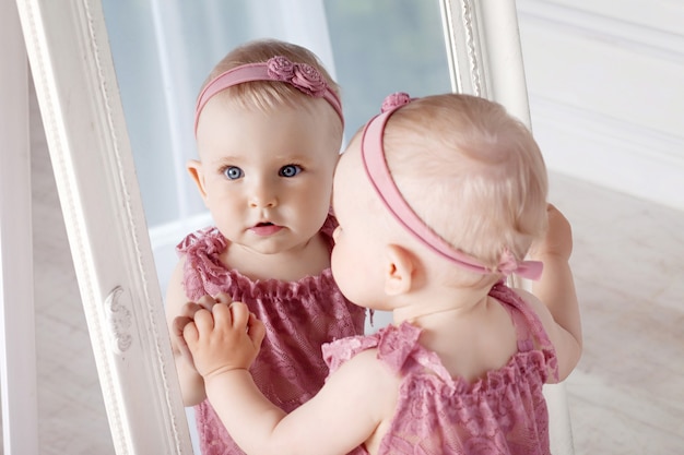 Niña bonita juega con un gran espejo. Retrato de la niña con reflejo en un espejo