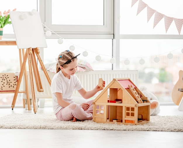 Niña bonita jugando con casa de muñecas