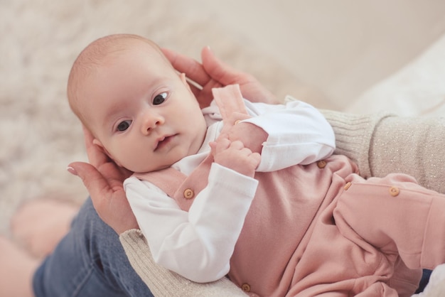 Niña bonita en manos de la madre en la habitación