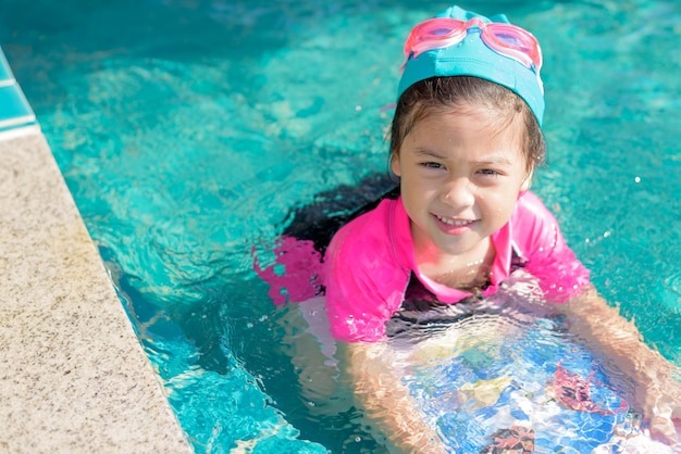 Niña bonita nadando en la piscina al aire libre y diviértete.