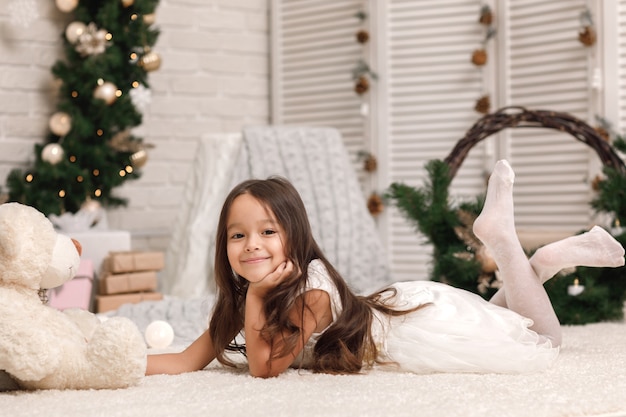 Niña bonita con un oso de peluche en Navidad