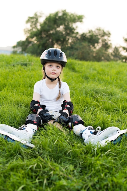 Niña bonita en patines en casco al aire libre en un hermoso día de verano