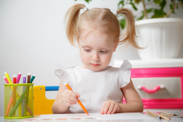 Niña bonita pintando con acuarelas en casa