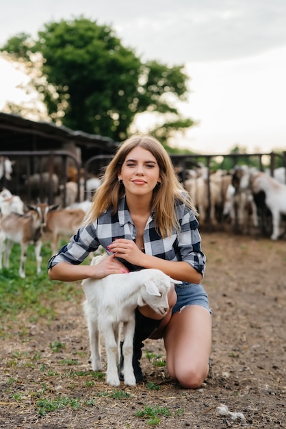 Foto una niña bonita posa en un rancho con cabras y otros animales.