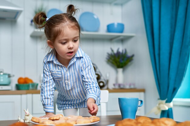 Niña bonita que busca comer algo dulce en la cocina