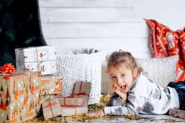 Una niña bonita con regalos y decoración navideña