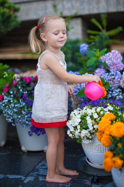 Niña bonita regando flores con una regadera