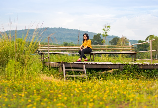 Foto niña bonita en silla de madera en campo de flor amarilla