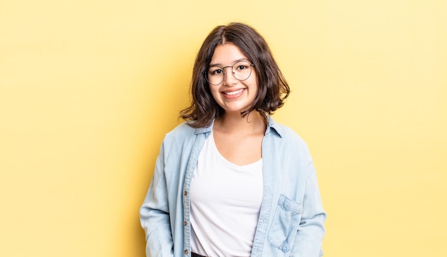 Niña bonita sonriendo alegre y casualmente con una expresión positiva, feliz, segura y relajada