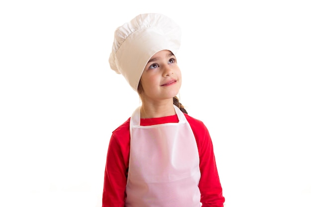 Niña bonita sosteniendo un rodillo y una espátula de cocina sobre fondo blanco en el estudio