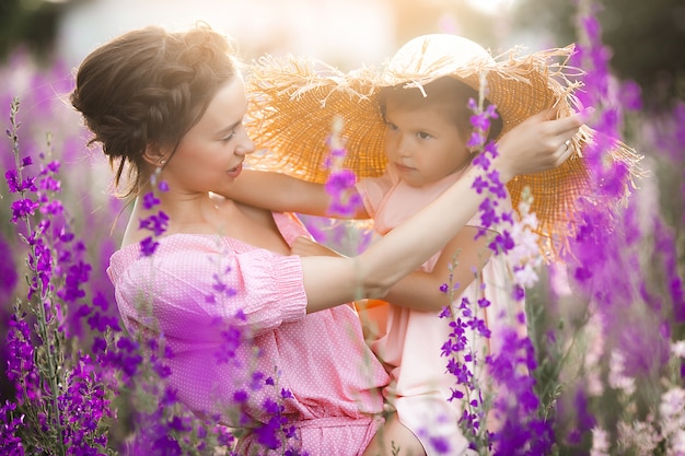 Niña bonita y su madre con flores. Familia al aire libre