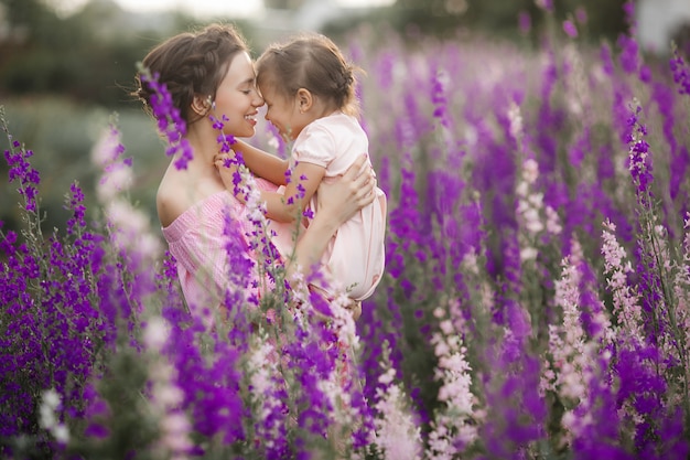 Niña bonita y su madre con flores. Familia al aire libre