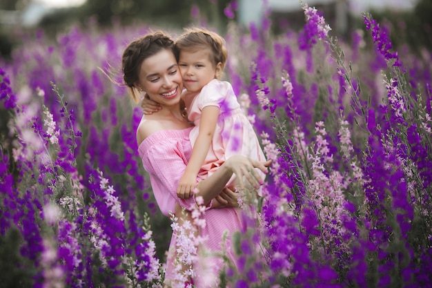 Niña bonita y su madre con flores. Familia al aire libre