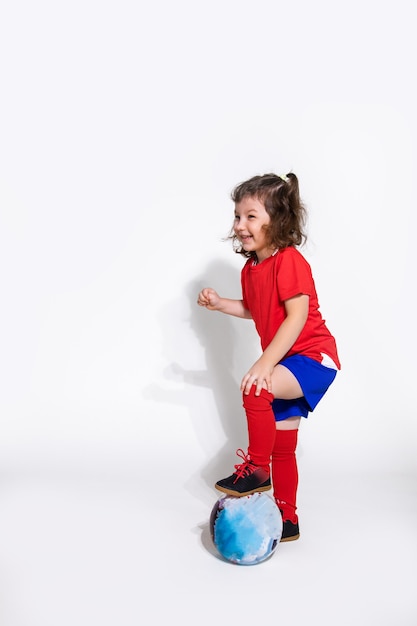 Niña bonita en uniforme de fútbol y con pelota