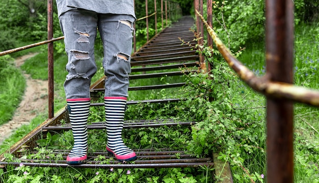 Una niña con botas de goma camina en el bosque en primavera lluviosa de cerca