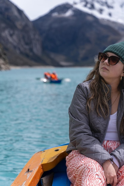 Una niña en un bote en una laguna rodeada de montañas nevadas