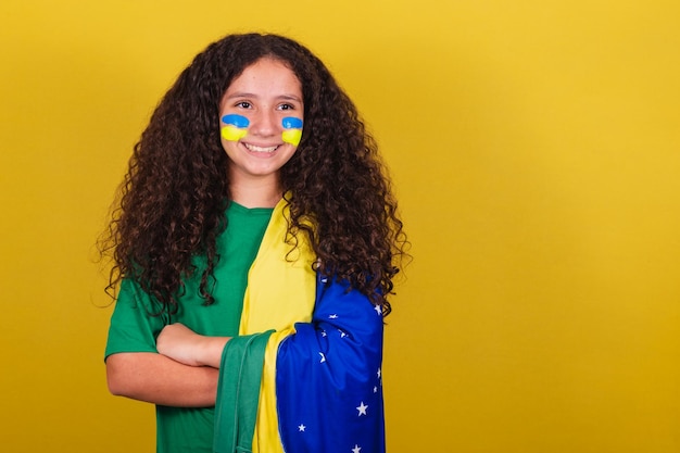 Niña brasileña aficionado al fútbol caucásico brazos cruzados optimista positivo