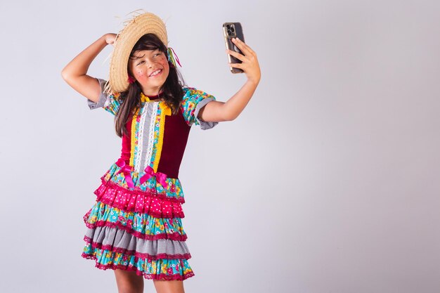 Foto niña brasileña con ropa de fiesta de junio tomando autorretrato