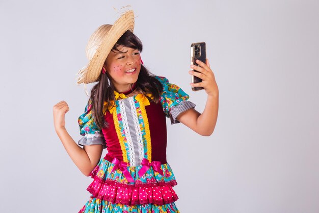 Foto niña brasileña con ropa de fiesta de junio tomando autorretrato