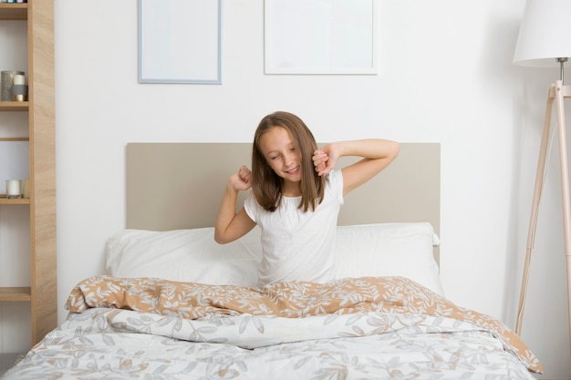 Niña de buen humor en pijama en el dormitorio