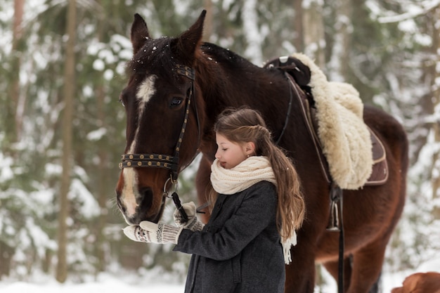 niña y caballo marrón en invierno en la naturaleza