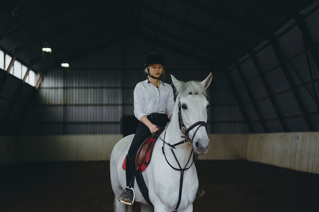 Una niña a caballo montando una arena