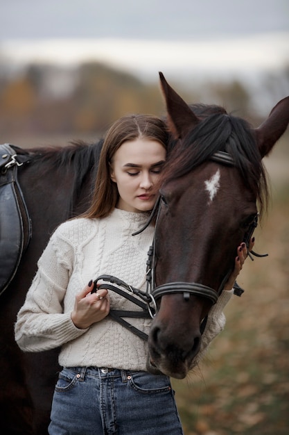 Una niña con un caballo en la naturaleza, un paseo otoñal con un animal.