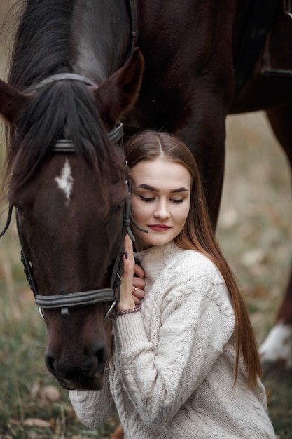 Una niña con un caballo en la naturaleza, un paseo otoñal con un animal.