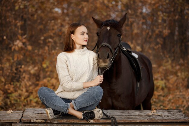 Una niña con un caballo en la naturaleza, un paseo otoñal con un animal.