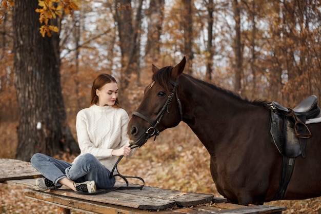 Una niña con un caballo en la naturaleza, un paseo otoñal con un animal.