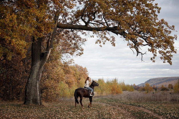 Una niña con un caballo en la naturaleza, un paseo otoñal con un animal.